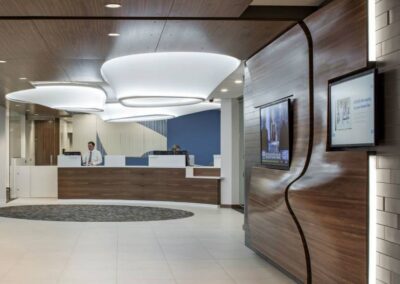 Commerical cabinetry and casework - a hospital with custom wall-paneling , built-in front desk area, and ceiling paneling flush with lighting